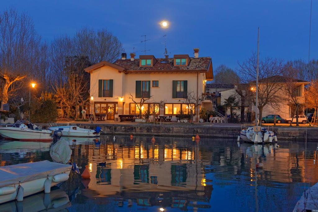 a house with boats in the water at night at Affittacamere Porticciolo in Castelnuovo del Garda