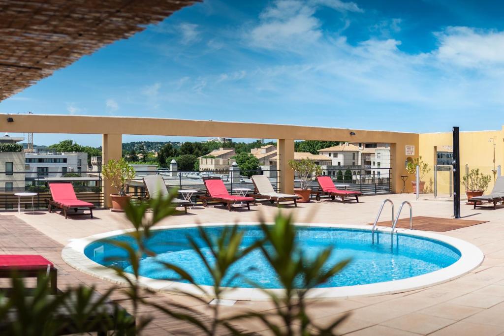 亞維儂的住宿－阿維農豪華酒店，一个带红色椅子的游泳池和一个庭院