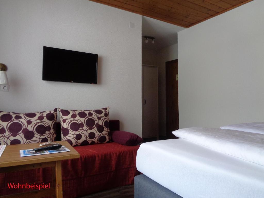 a hotel room with a bed and a couch and a tv at Gasthof Panorama in Obsteig