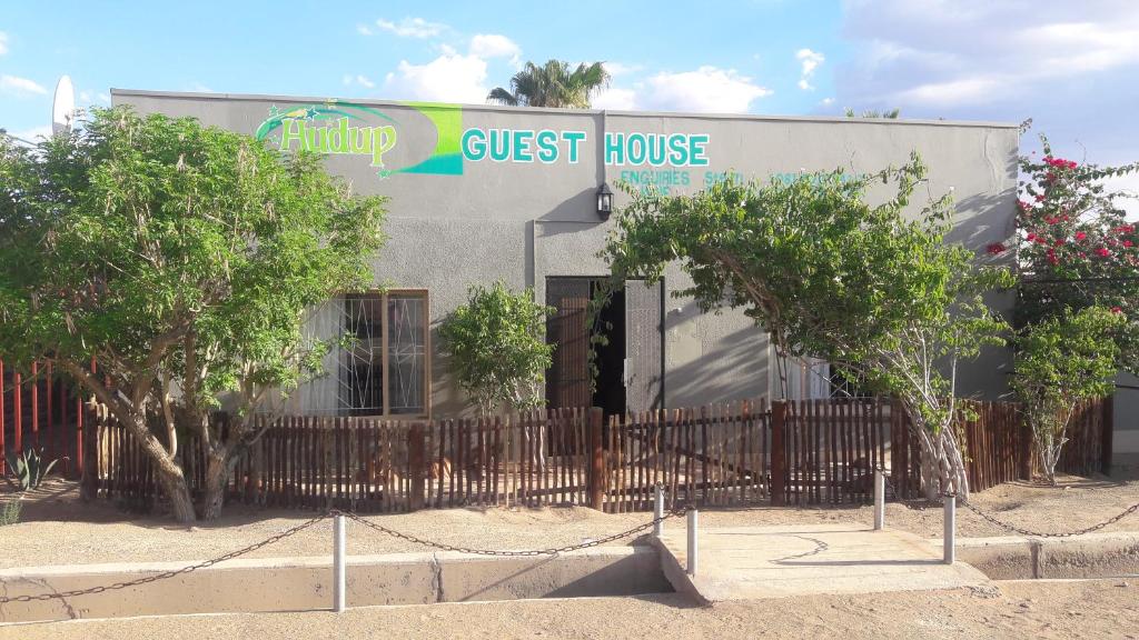 a guest house with a fence and trees in front of it at HUDUP Guesthouse in Maltahöhe