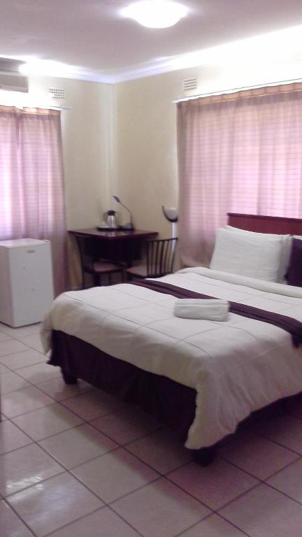 een slaapkamer met een groot bed en een tafel bij Hardrock Guest House in Francistown