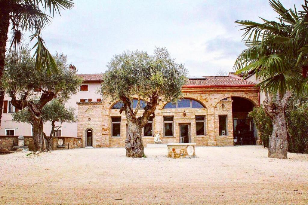 un grand bâtiment avec des arbres devant lui dans l'établissement Agriturismo le Fontanelle da Valente, à Montichiari