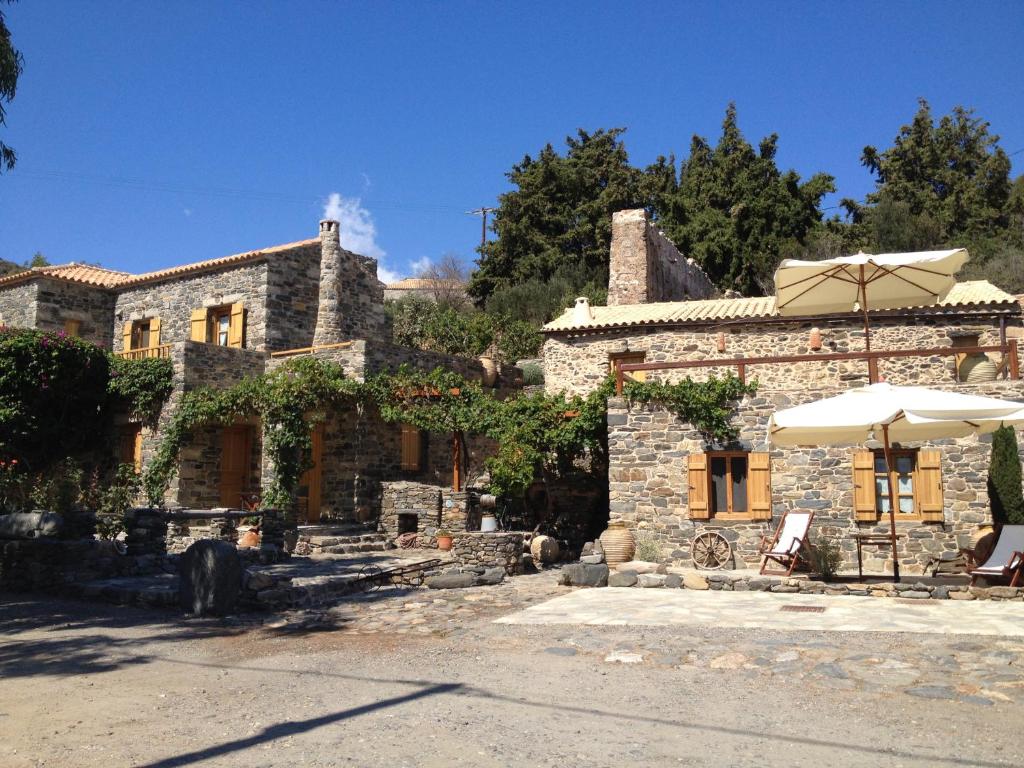 a stone house with an umbrella and a table and an umbrella at Neromylos in Agia Pelagia