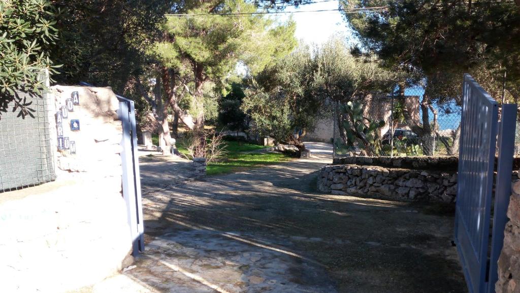 une porte menant à une allée avec une clôture et des arbres dans l'établissement Villa Aquarium, à Gagliano del Capo