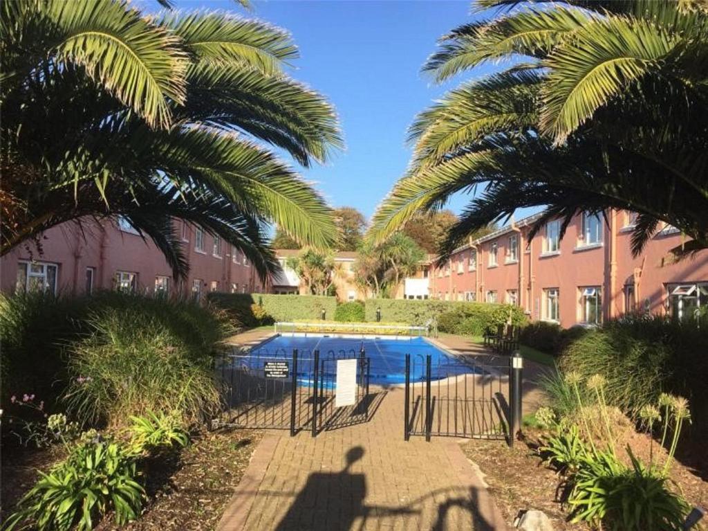 a swimming pool in a courtyard with palm trees at 57 New Esplanade Court, Beach Close By Pool View in Paignton