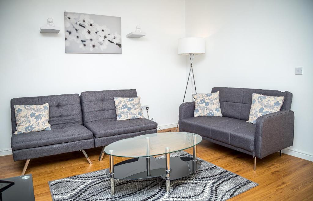 a living room with two couches and a table at Luxuriant Apartments in Northampton