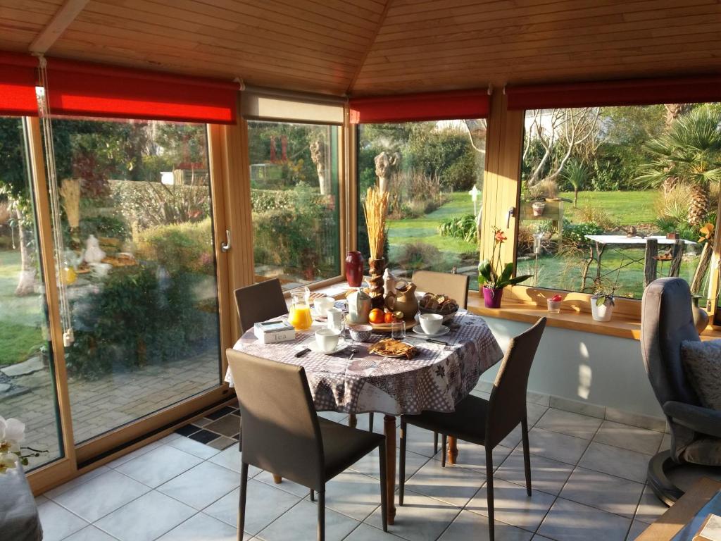 a dining room with a table and chairs and large windows at Chambres d'hotes de Pouldiguy in Lannion