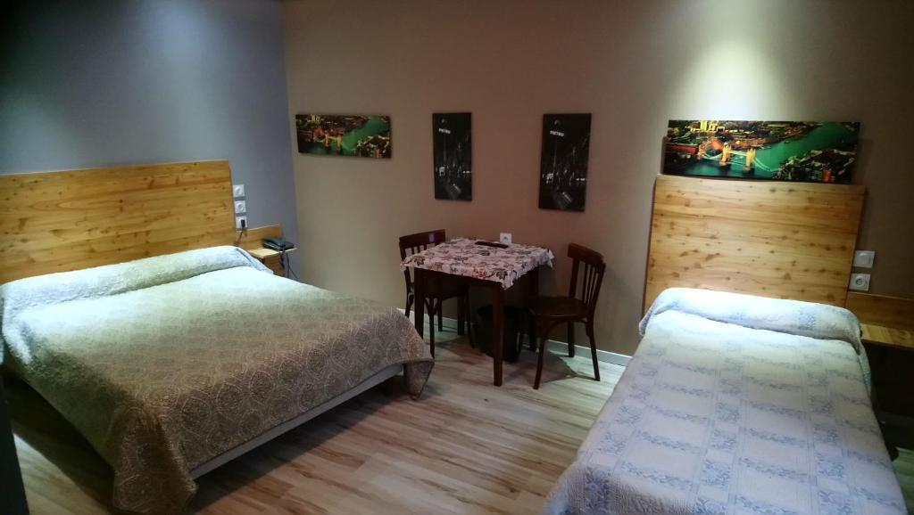 a bedroom with two beds and a table in it at Hotel de la Poste in Saint-Claude