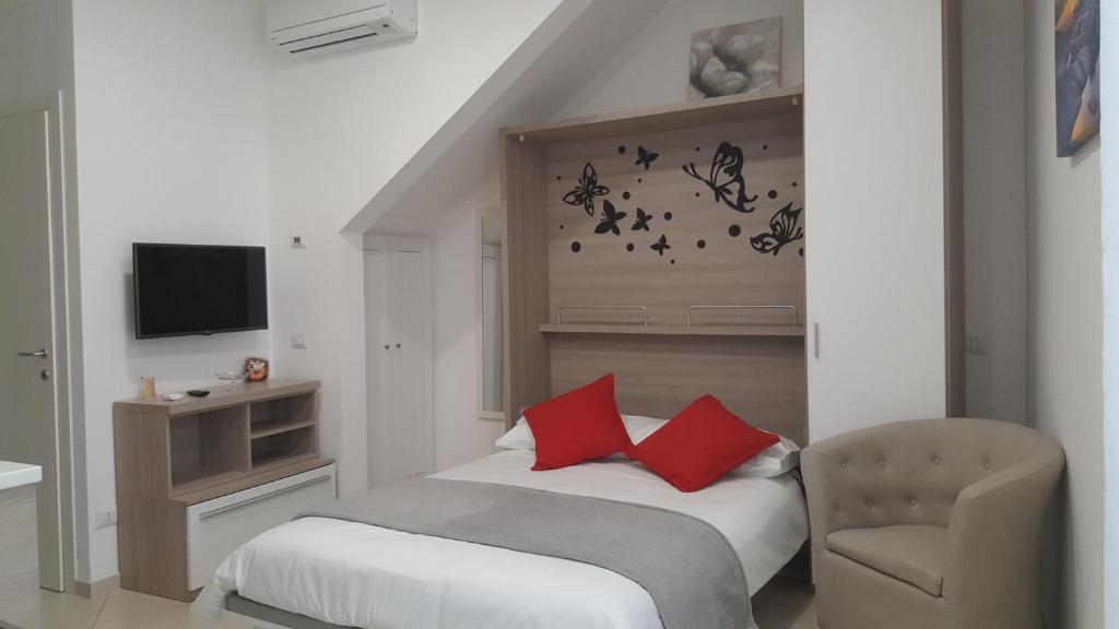 Un dormitorio con una cama con almohadas rojas y una silla en Monolocale turistico Valentini, en Albano Laziale
