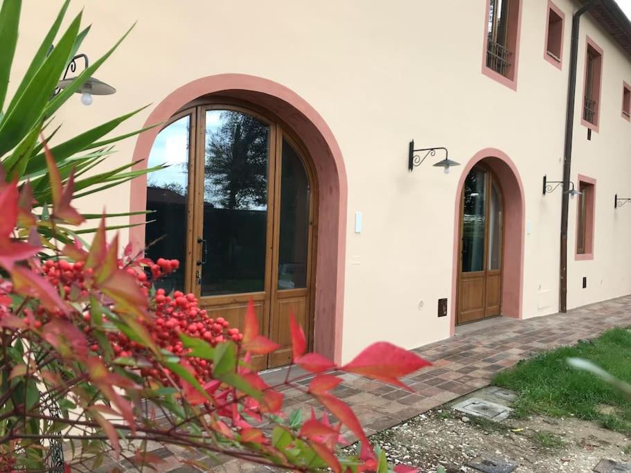 a house with two doors and red flowers in front at Villa Leonardo in Vinci