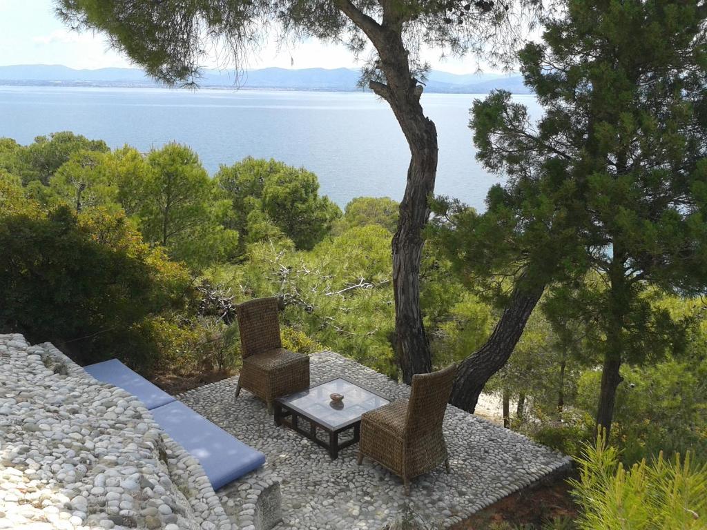 a patio with a table and chairs and a view of the water at Villa Heleni in Vouliagmeni Lake