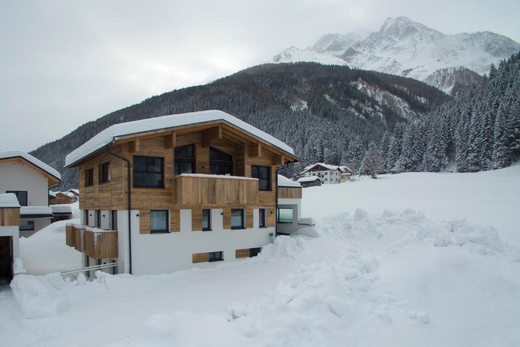 een gebouw bedekt met sneeuw met bergen op de achtergrond bij Chalet Bella in Pettneu am Arlberg