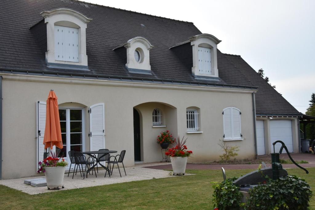Véretz的住宿－Le Clos du Vieux Port，白色的房子,配有桌椅和遮阳伞