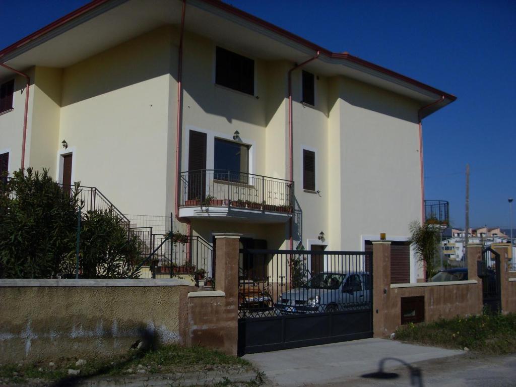 a white house with a black gate in front of it at Yellow House in San Sostene