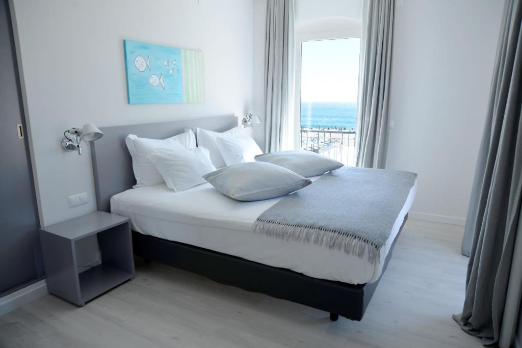a bedroom with a bed with pillows and a window at Hotel Mar Bravo in Nazaré