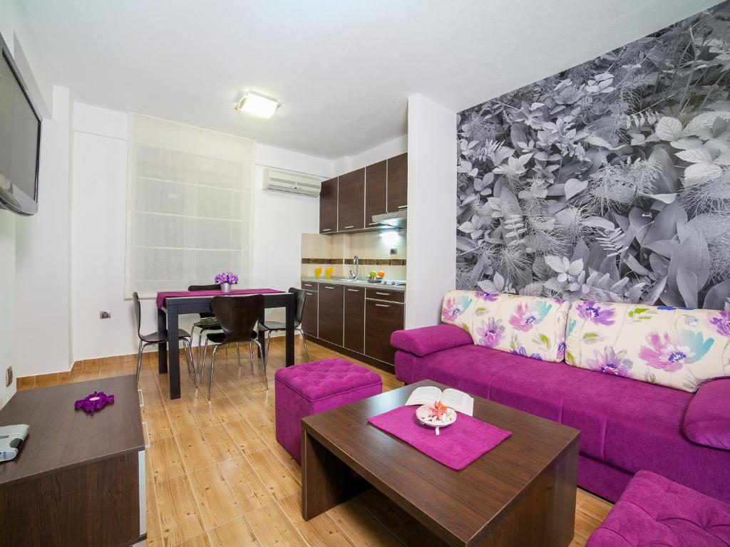 a living room with a purple couch and a table at Apartments Raymond in Sveti Stefan