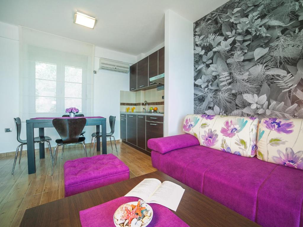 a living room with a purple couch and a table at Apartments Raymond in Sveti Stefan