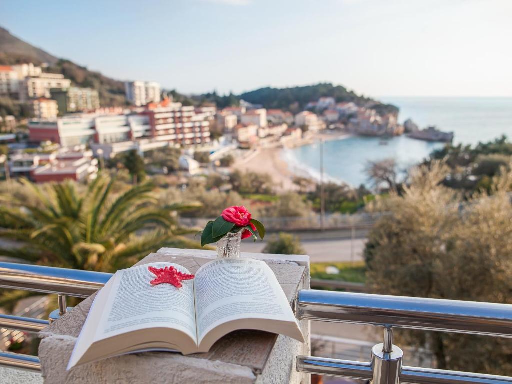 a book sitting on a ledge with a flower on it at Apartments Raymond in Sveti Stefan