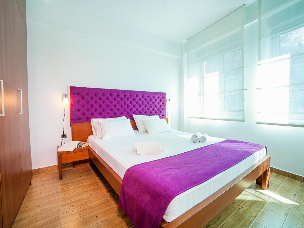a bedroom with a large bed with a purple headboard at Apartments Raymond in Sveti Stefan