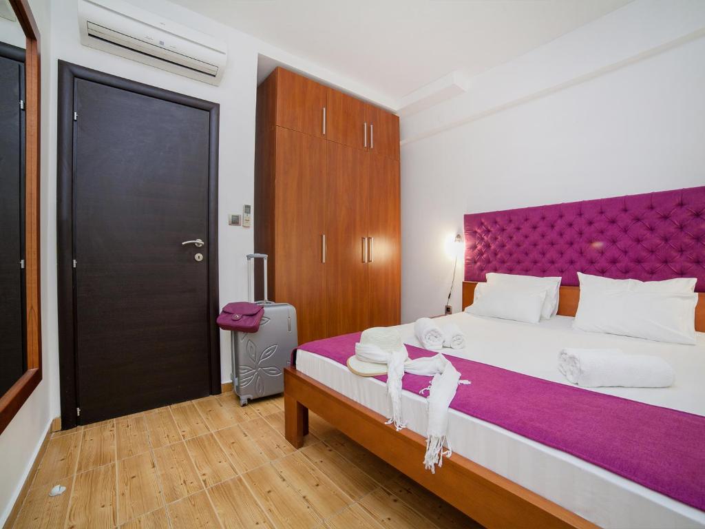a bedroom with a large bed with a purple headboard at Apartments Raymond in Sveti Stefan