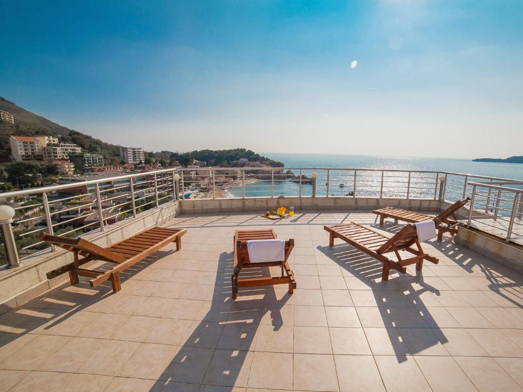 a balcony with benches and a view of the water at Apartments Raymond in Sveti Stefan