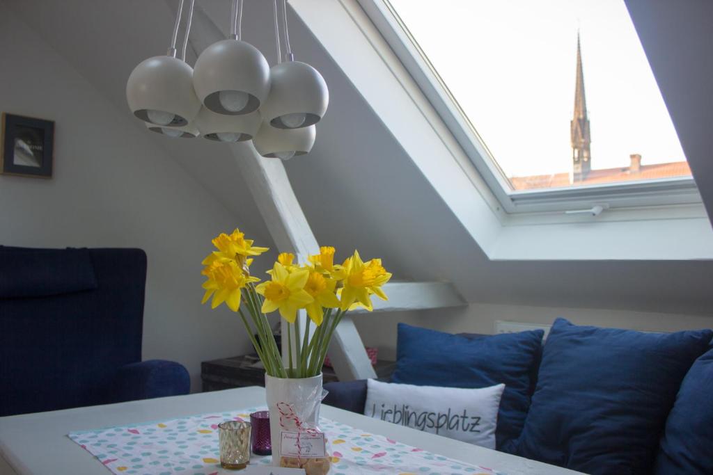 un vaso di fiori gialli su un tavolo con un divano blu di Stadtflucht Lüneburg: Ferienwohnungen Innenstadt a Lüneburg