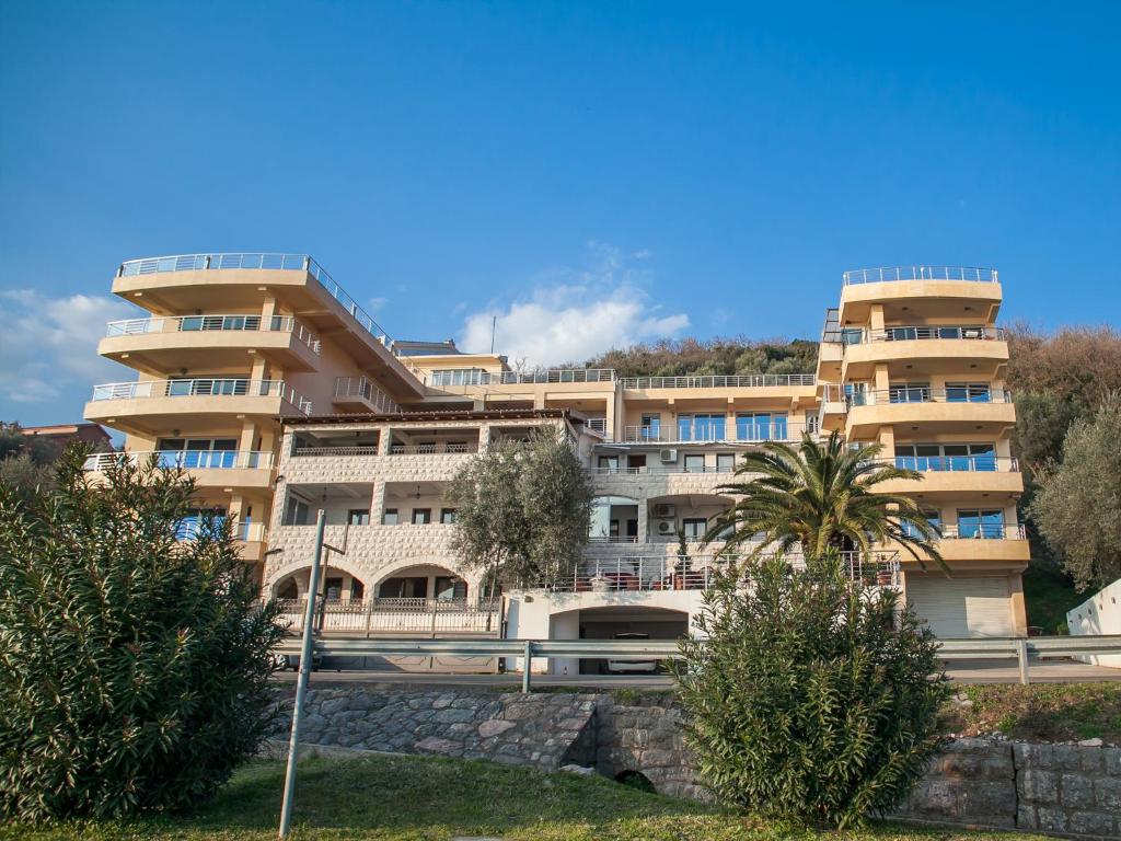 a large apartment building with trees in front of it at Apartments Raymond in Sveti Stefan