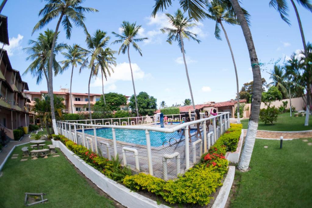 a view of a pool at a resort with palm trees at Flat Barra de São miguel mobiliado in Barra de São Miguel