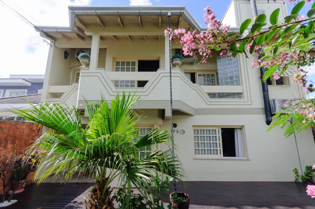 une maison blanche avec des palmiers devant elle dans l'établissement casa das flores, à Canoas