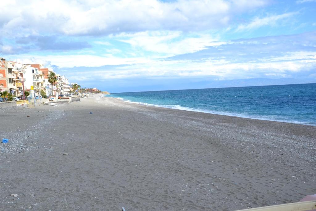 an empty beach with buildings and the ocean at Hotel Caudullo in Letojanni