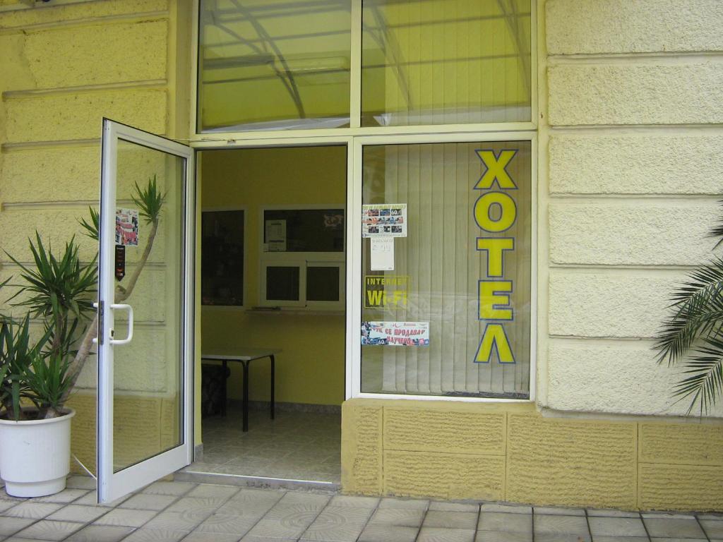 un edificio amarillo con una señal de salida en la ventana en Hotel Maritsa, en Lyubimets