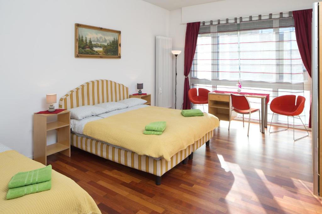 a bedroom with two beds and a table and chairs at Rooms Al Festival in Locarno