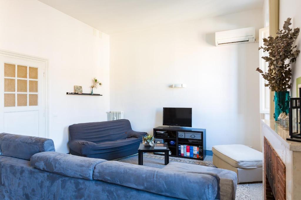 ein Wohnzimmer mit einem blauen Sofa und einem TV in der Unterkunft PIAZZA MAZZINI APARTMENT in Rom