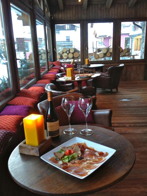 a table with a plate of food and wine glasses at Hotel Punta Maquignaz in Breuil-Cervinia