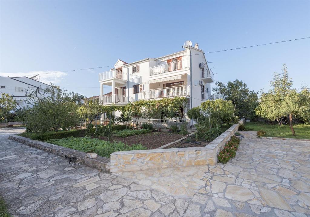 a large white building with a stone path in front of it at Apartments Summertime in Srima