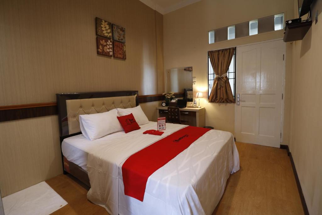 a bedroom with a large bed with a red blanket at RedDoorz Plus near Universitas Sumatera Utara in Medan