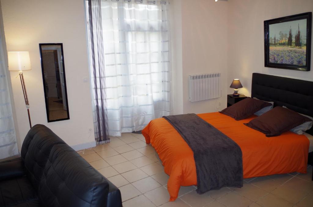 een slaapkamer met een groot bed en een oranje deken bij La Miellerie in Saint-Antoine