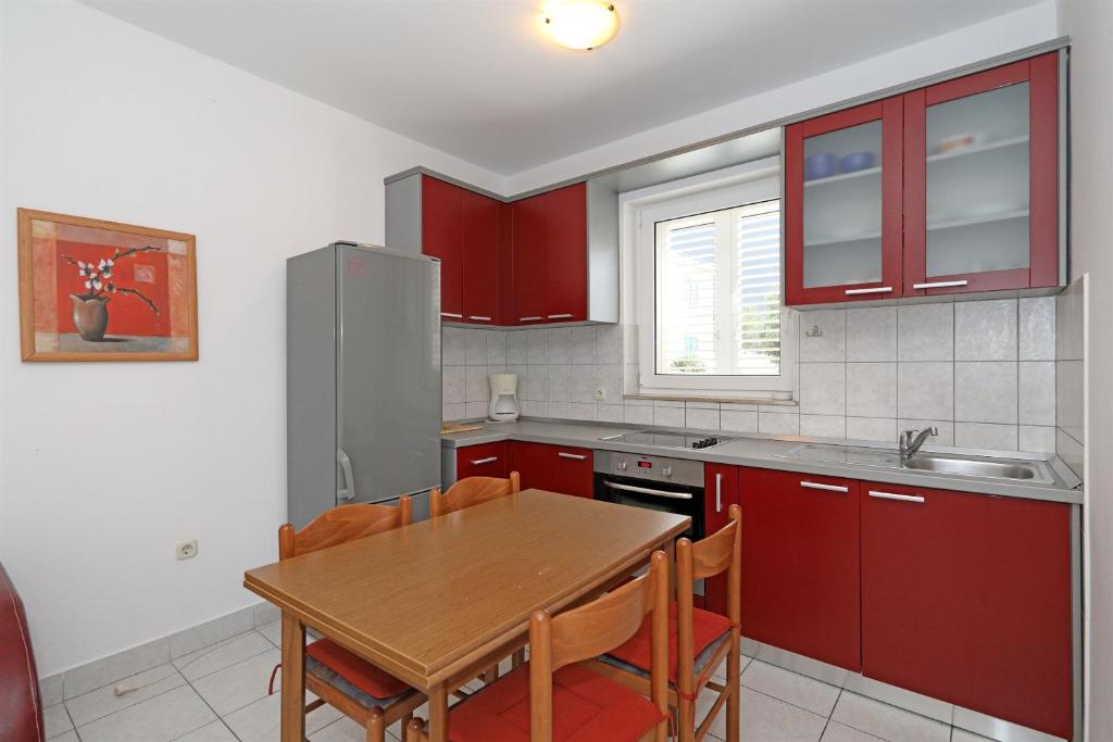 a kitchen with red cabinets and a wooden table at Apartments Karolina in Novalja