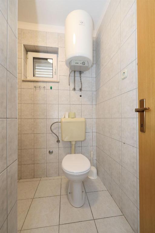 a bathroom with a toilet and a light on the wall at Apartments Karolina in Novalja
