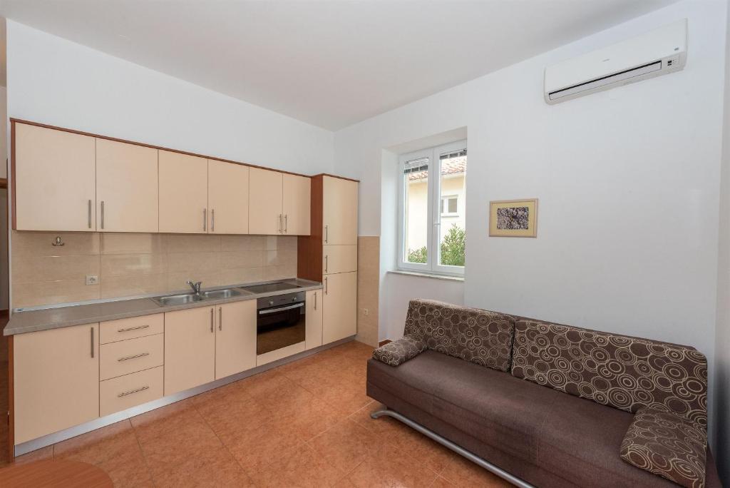 a living room with a couch and a kitchen at Apartments Karolina in Novalja