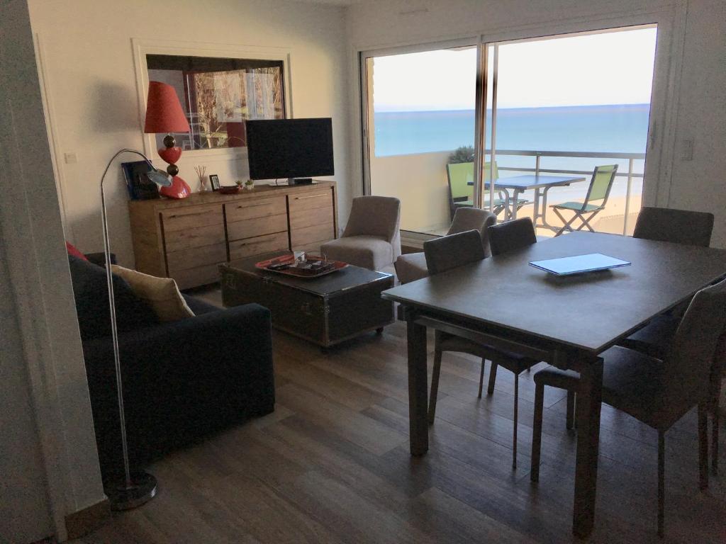 a living room with a table and a dining room with a balcony at Appartement, vue mer à 150m de la plage in Trouville-sur-Mer