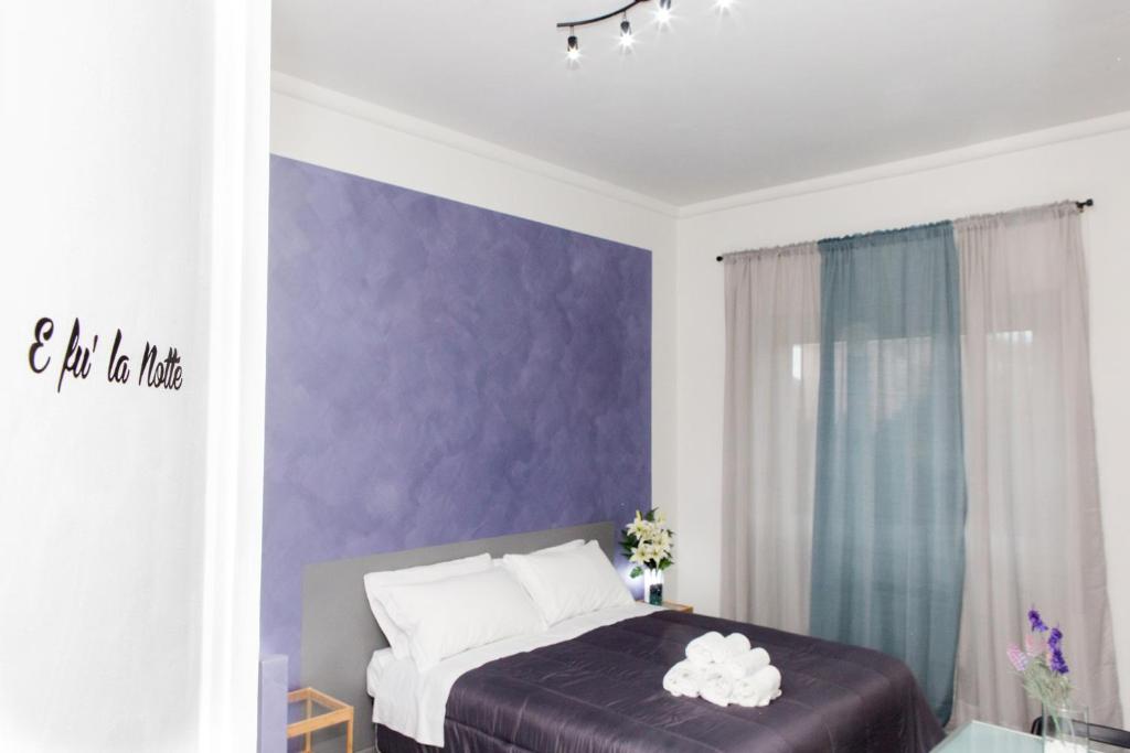 a bedroom with purple walls and a bed with white pillows at Foresteria Boccadasse in Genoa