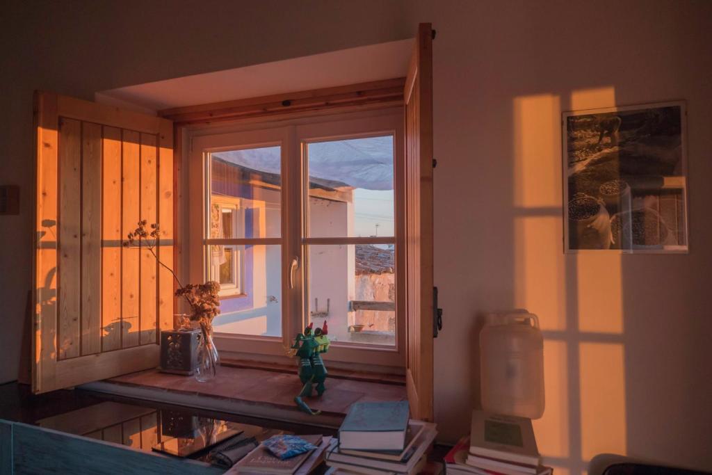 a room with a window with books and a table at Casa das Romãs in Messejana