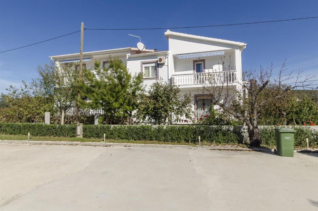 a white house with a fence in front of it at Apartments Verica in Sukošan