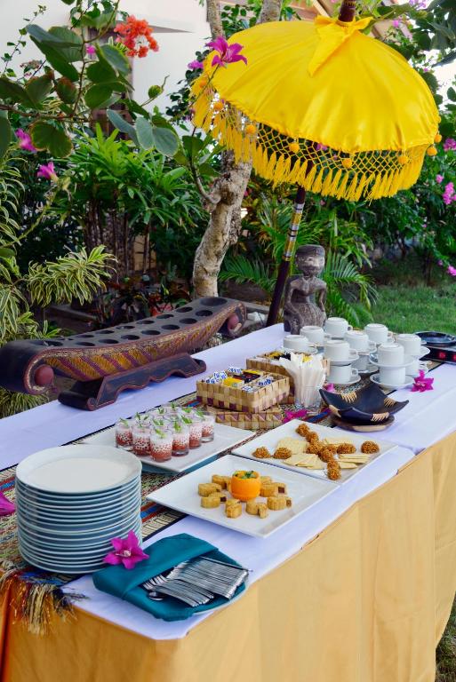 a table with plates of food and an umbrella at Cocotinos Sekotong Lombok in Sekotong