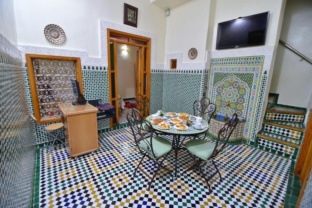 um quarto com uma mesa e cadeiras e uma televisão em Dar Ikram em Fez