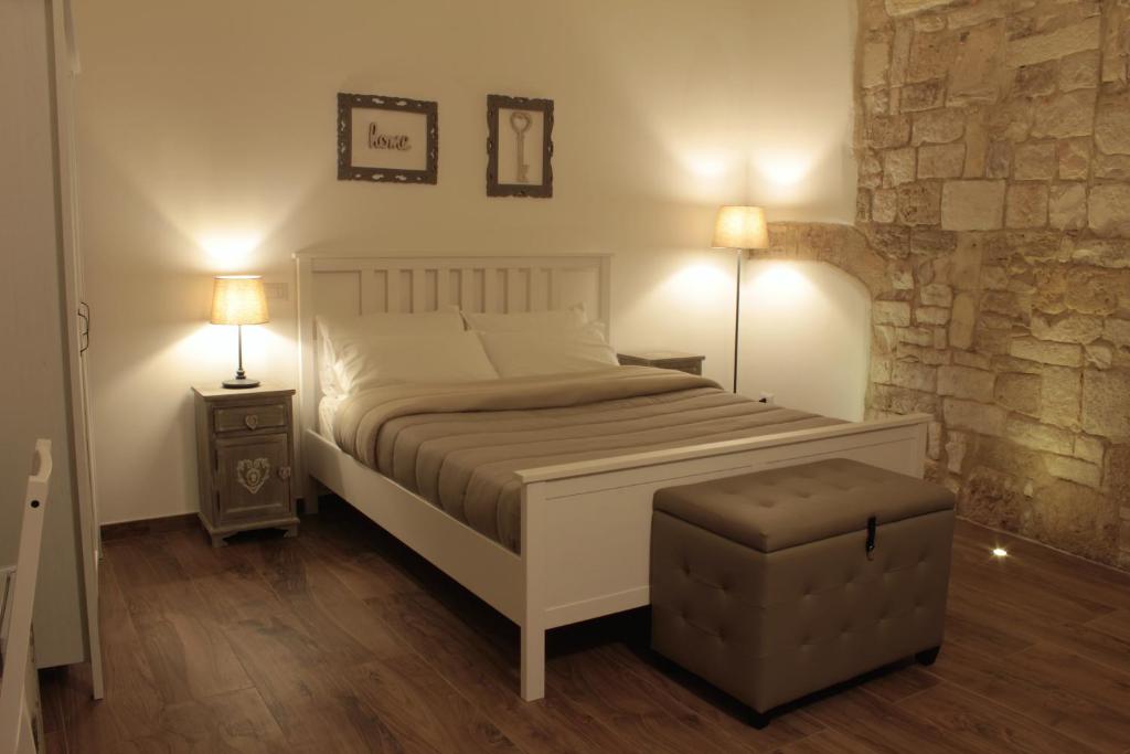 a bedroom with a white bed and a stone wall at DeShome Guest House in Bari