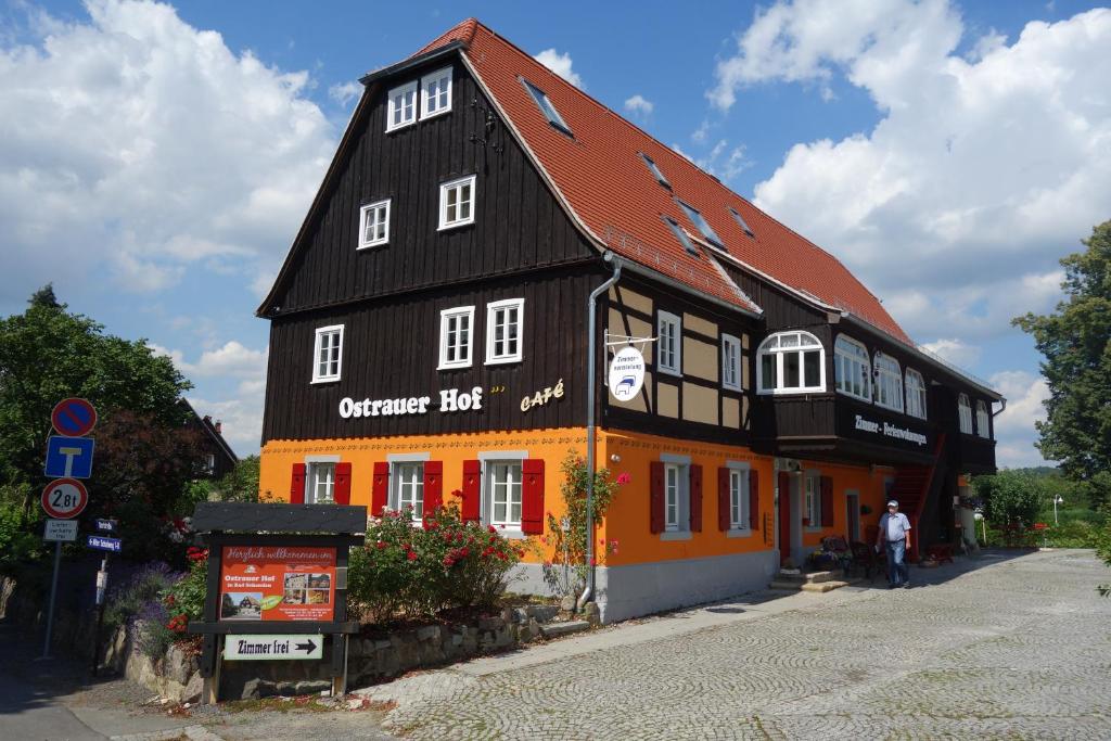 Un bâtiment orange et noir avec un homme debout devant lui dans l'établissement Ferienhaus Ostrauer Hof, à Bad Schandau