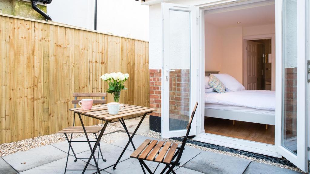un patio con una mesa y sillas y una cama en The Wing -Near to the beaches and Bournemouth University en Bournemouth