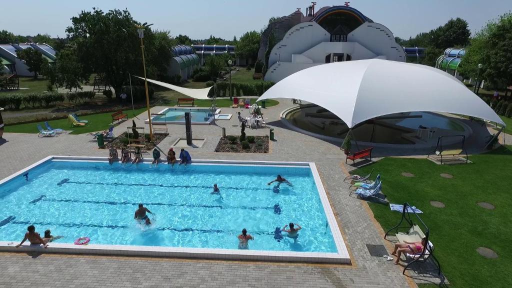 um grupo de pessoas em uma piscina com um guarda-sol em Hőforrás Hotel em Gyula